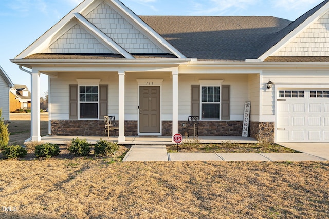 craftsman inspired home with an attached garage, covered porch, and stone siding