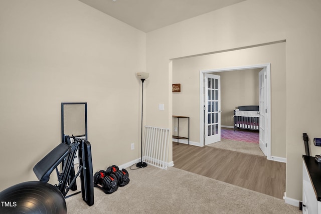 exercise room with carpet floors, baseboards, wood finished floors, and french doors