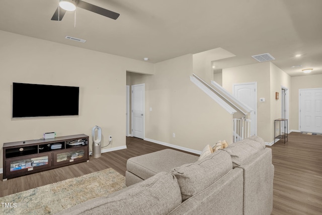 living area featuring stairs, visible vents, baseboards, and wood finished floors