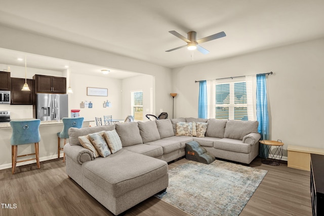 living room featuring ceiling fan, plenty of natural light, wood finished floors, and baseboards