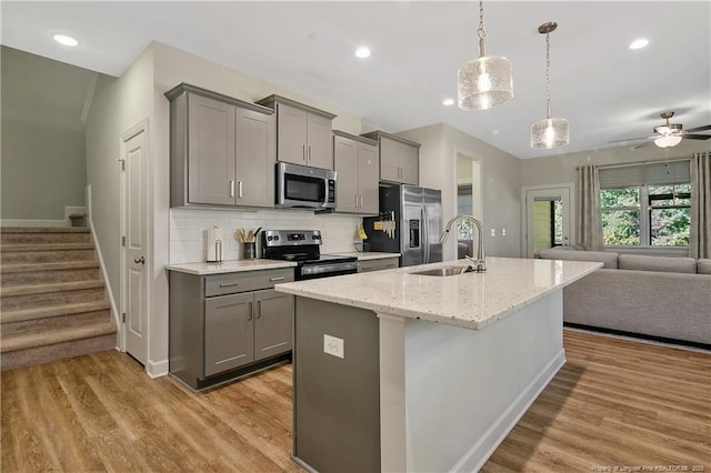 kitchen with light wood-style floors, appliances with stainless steel finishes, open floor plan, and gray cabinetry