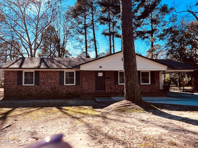 view of front of home featuring driveway, a carport, and brick siding