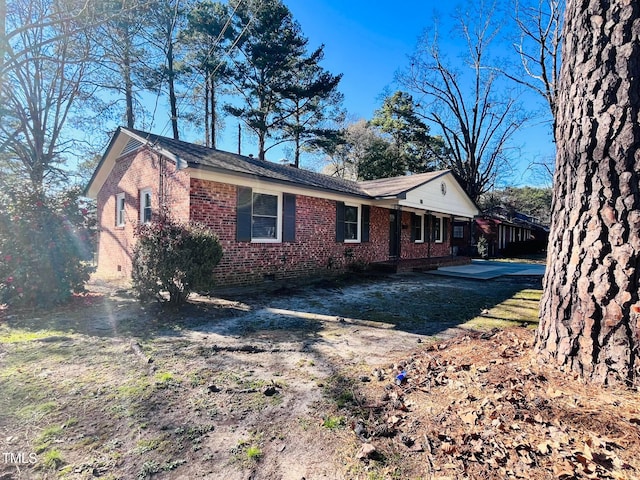 view of home's exterior with crawl space and brick siding