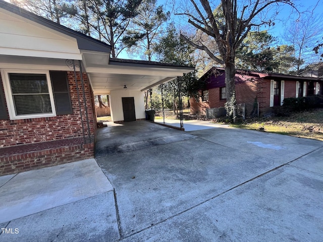 view of side of home featuring driveway, a carport, and brick siding