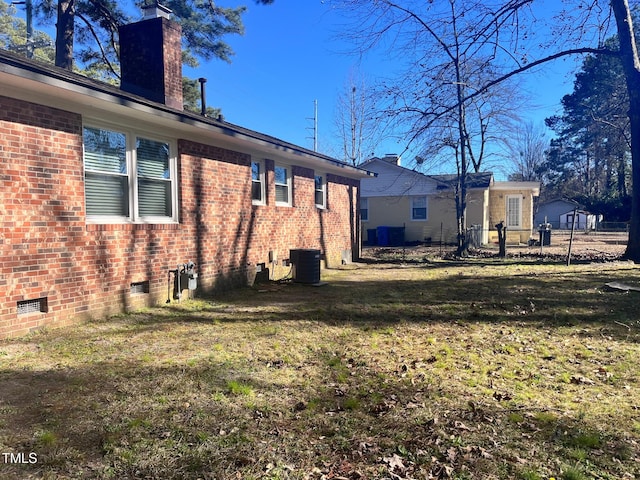 exterior space with brick siding, crawl space, a chimney, and a lawn