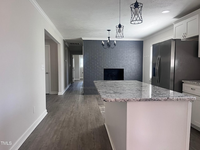 kitchen featuring stainless steel fridge, a kitchen island, dark wood-style flooring, and crown molding