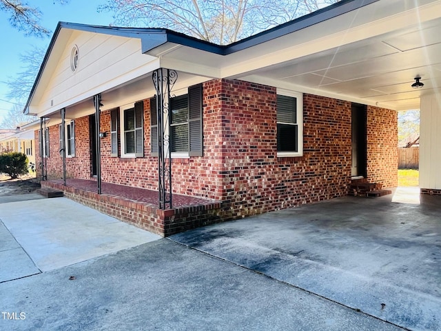 view of home's exterior featuring a carport, brick siding, and driveway