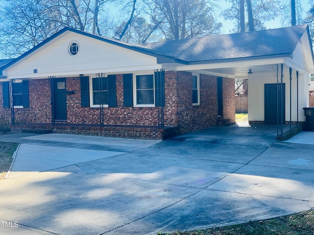 view of front of home with brick siding, an attached carport, driveway, and a shingled roof