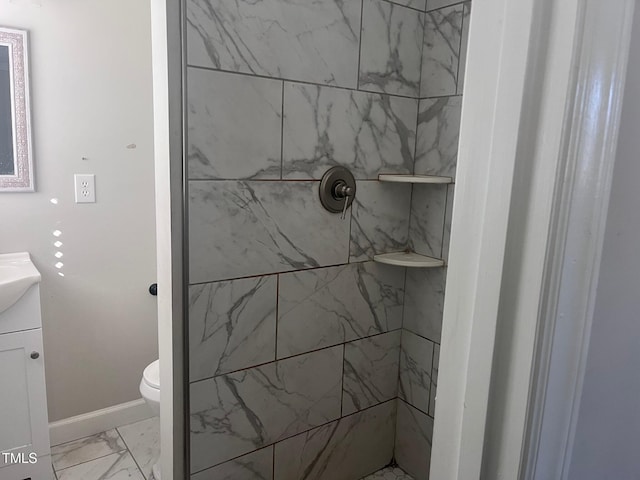 bathroom featuring toilet, vanity, baseboards, marble finish floor, and a tile shower