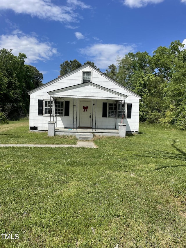 bungalow-style home featuring covered porch and a front lawn