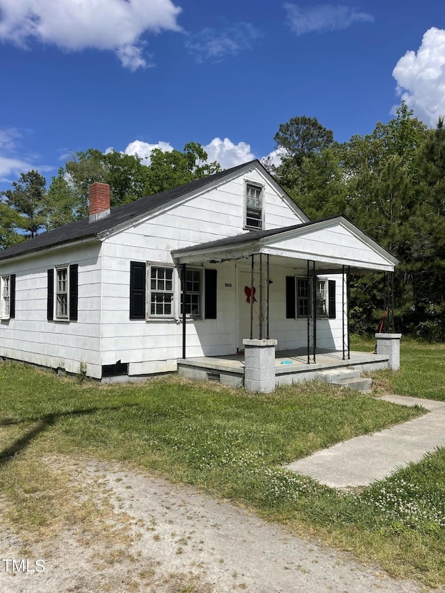 view of front of home featuring a porch, a front yard, and a chimney