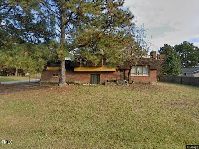 tri-level home featuring a chimney, fence, a front lawn, and brick siding