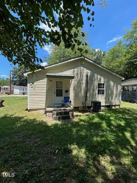 rear view of property featuring a yard and central AC unit