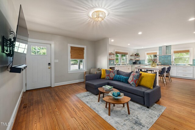 living room featuring baseboards, recessed lighting, light wood-style floors, and a notable chandelier