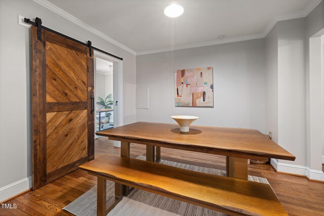 dining area featuring a barn door, wood finished floors, and ornamental molding