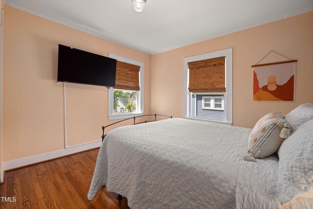 bedroom with baseboards, ornamental molding, and wood finished floors