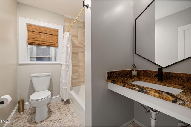 bathroom with tile patterned flooring, shower / tub combo, a sink, baseboards, and toilet