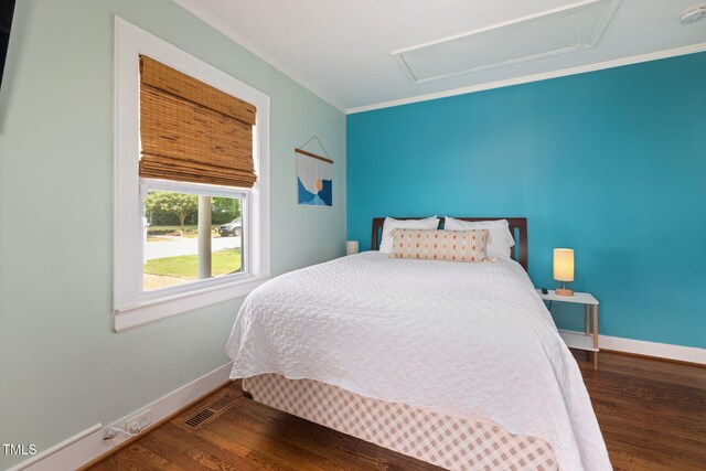 bedroom with baseboards, attic access, wood finished floors, and visible vents
