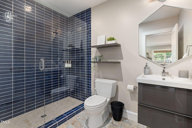 bathroom featuring vanity, baseboards, toilet, and tiled shower
