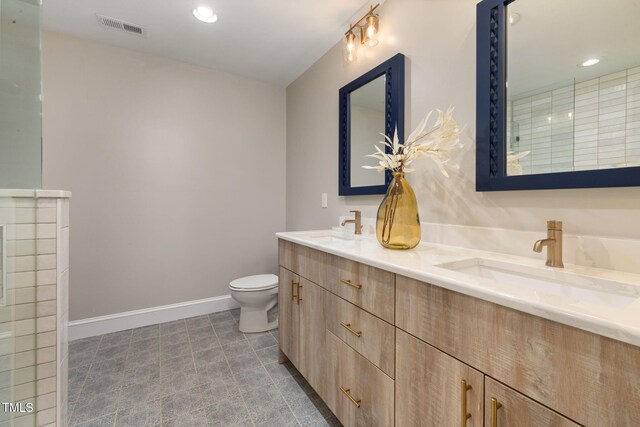 bathroom with a sink, double vanity, toilet, baseboards, and visible vents