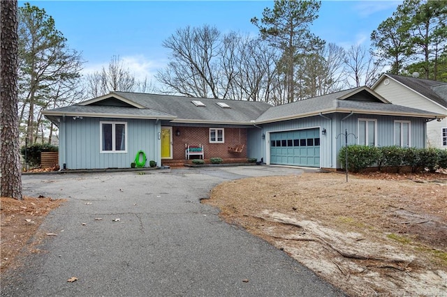 single story home featuring driveway, a garage, and brick siding