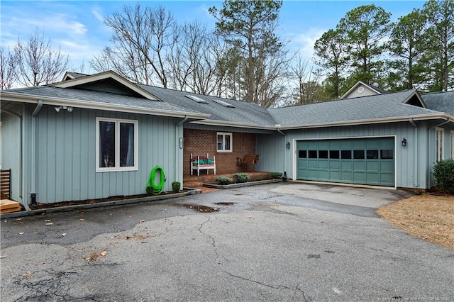 ranch-style home with aphalt driveway, brick siding, a shingled roof, and an attached garage