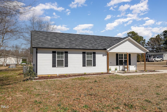 view of front of house featuring roof with shingles, a porch, and a front yard