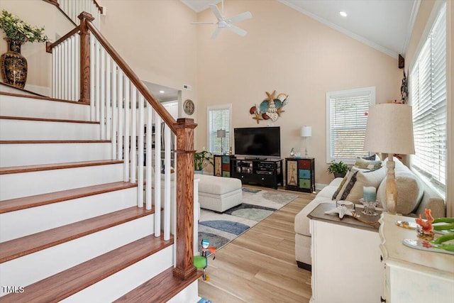 living room featuring a ceiling fan, stairway, wood finished floors, crown molding, and high vaulted ceiling