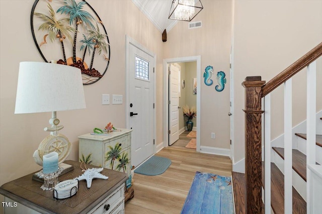 entryway featuring light wood-style flooring, visible vents, baseboards, ornamental molding, and stairway