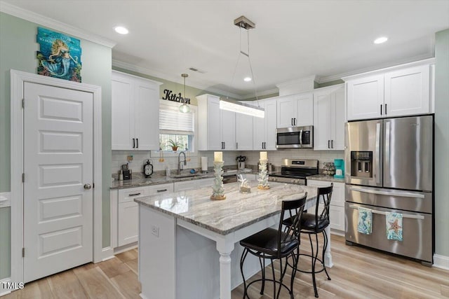 kitchen with appliances with stainless steel finishes, white cabinetry, backsplash, and light wood finished floors