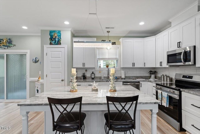 kitchen featuring appliances with stainless steel finishes, light wood-type flooring, a kitchen bar, and tasteful backsplash