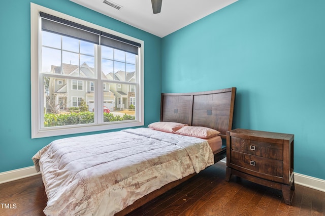 bedroom with baseboards, visible vents, a ceiling fan, a residential view, and wood finished floors