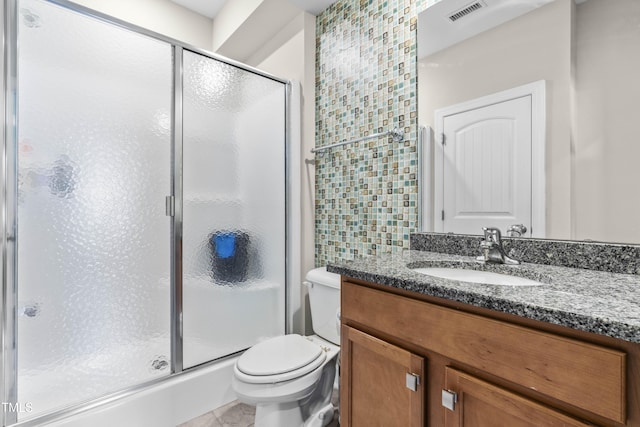 bathroom featuring toilet, vanity, a shower stall, and visible vents