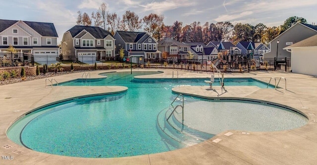 pool with a patio area, fence, and a residential view