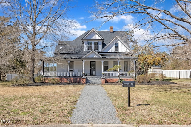 view of front of house featuring a chimney, a porch, board and batten siding, fence, and a front lawn