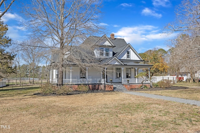 view of front of home featuring a chimney, fence, a front lawn, a porch, and board and batten siding