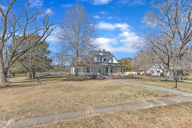 view of front of home with a front yard, covered porch, and a chimney