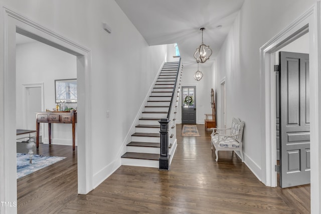 entrance foyer featuring a notable chandelier, stairs, baseboards, and dark wood-type flooring