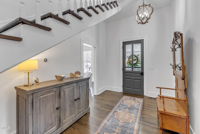 foyer entrance featuring a chandelier, dark wood-type flooring, and baseboards