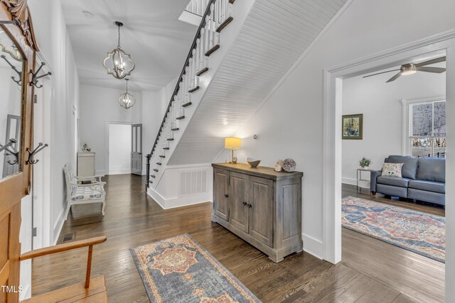 foyer entrance featuring stairs, dark wood-style flooring, visible vents, high vaulted ceiling, and ceiling fan with notable chandelier