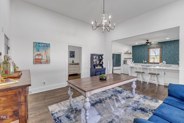 interior space with ceiling fan with notable chandelier, a high ceiling, wood finished floors, and baseboards