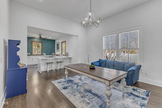 home office with ceiling fan with notable chandelier, a sink, dark wood finished floors, and baseboards