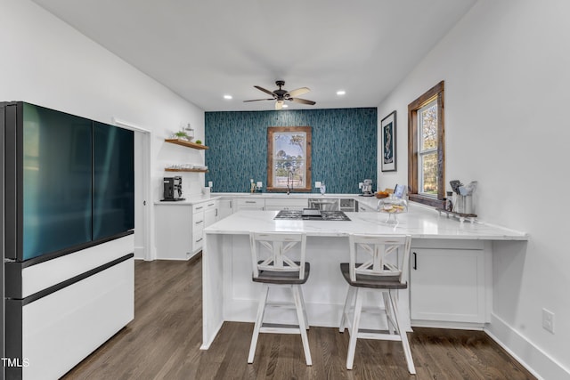 kitchen featuring light stone counters, a peninsula, high end refrigerator, white cabinetry, and open shelves