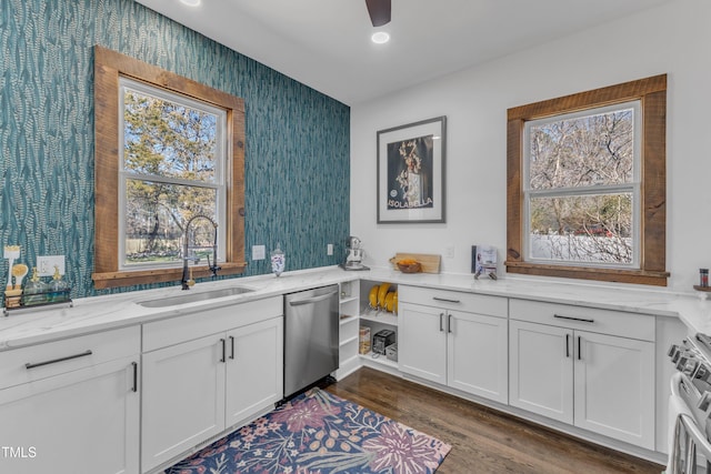 interior space featuring wallpapered walls, white cabinets, appliances with stainless steel finishes, light stone countertops, and a sink