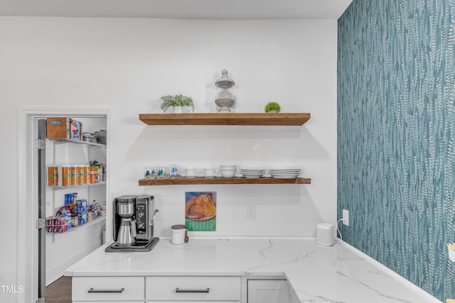 interior space featuring open shelves, light stone countertops, and white cabinets