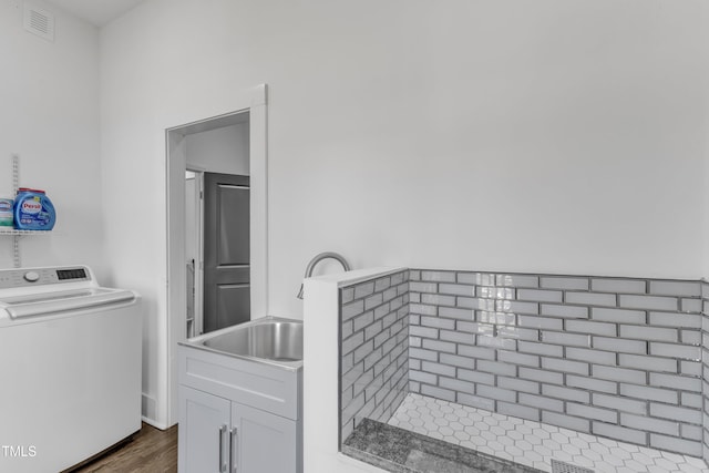 clothes washing area featuring a sink, visible vents, cabinet space, washer / clothes dryer, and dark wood finished floors