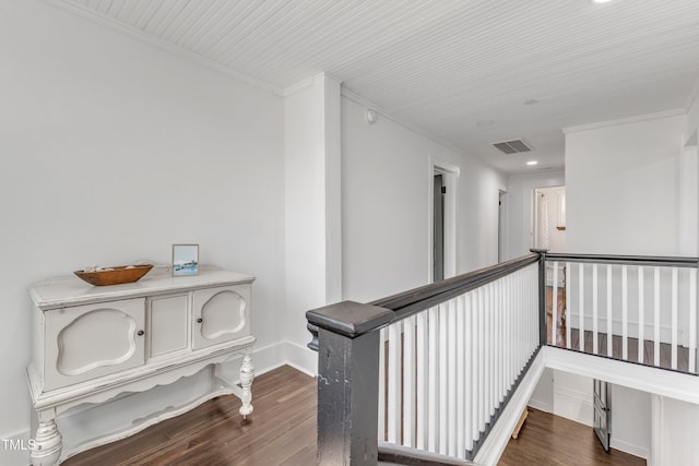 hallway featuring visible vents, dark wood-type flooring, ornamental molding, an upstairs landing, and baseboards