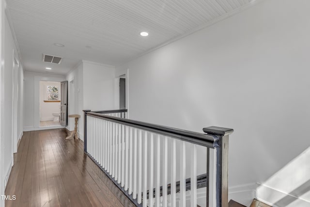 corridor featuring an upstairs landing, baseboards, visible vents, hardwood / wood-style floors, and crown molding