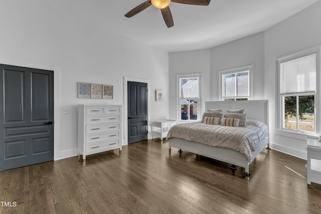 bedroom featuring ceiling fan, multiple windows, dark wood-style flooring, and baseboards