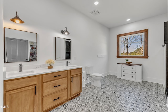 full bathroom with toilet, double vanity, visible vents, and a sink